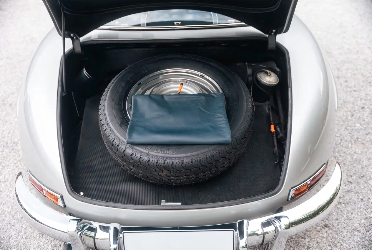 Open trunk of the silver 300 SL showing the spare wheel and blue luggage cover