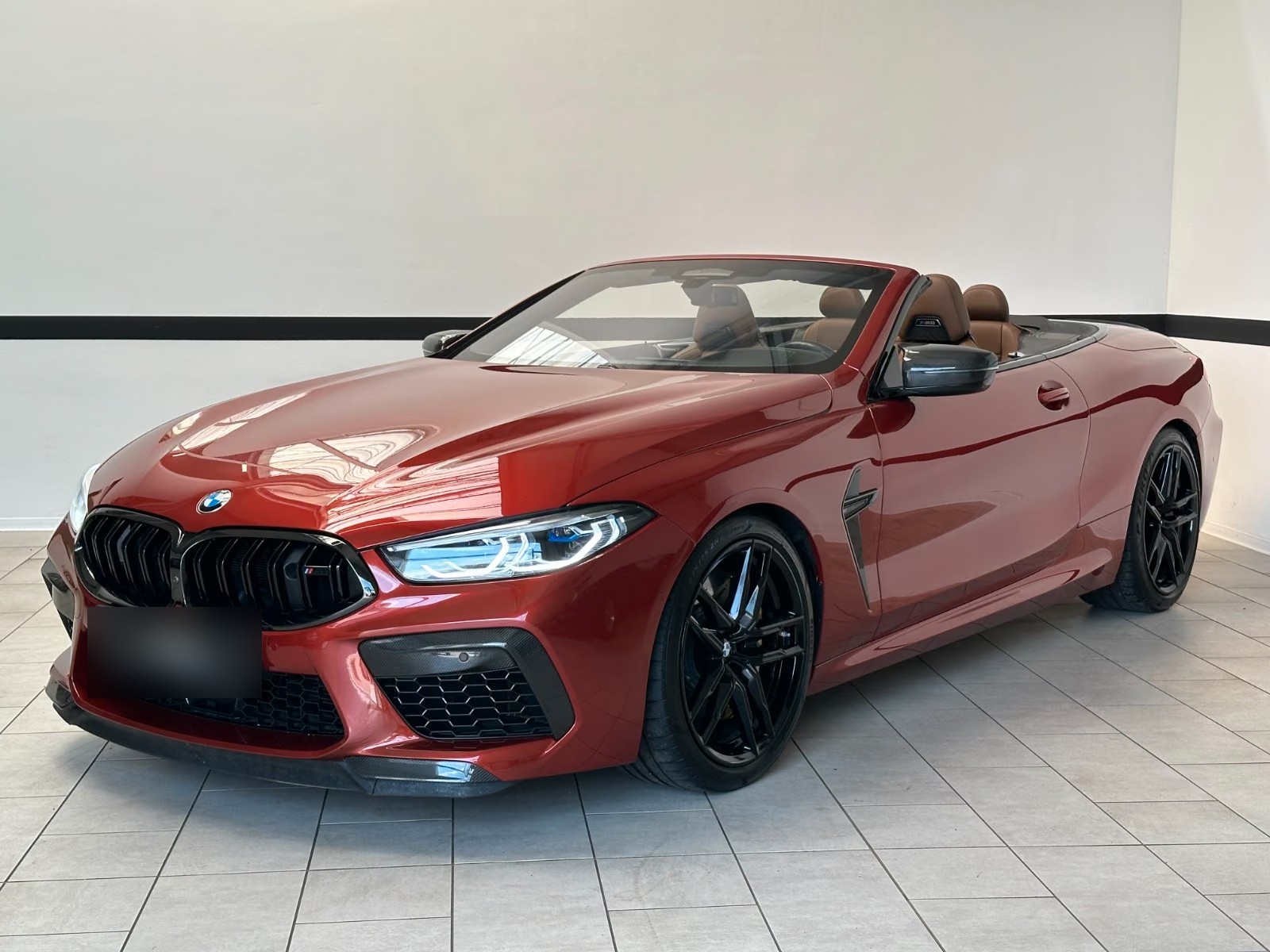 BMW M8 Competition Cabrio in Motegi Rot metallic, front three-quarter view with the roof down and black M alloy wheels.