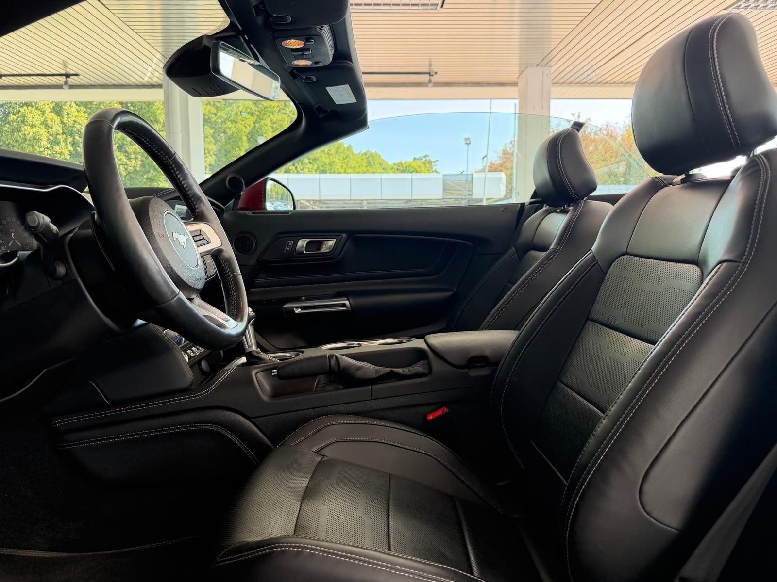Driver-side interior view of the Ford Mustang GT Convertible with black leather seats and steering wheel.