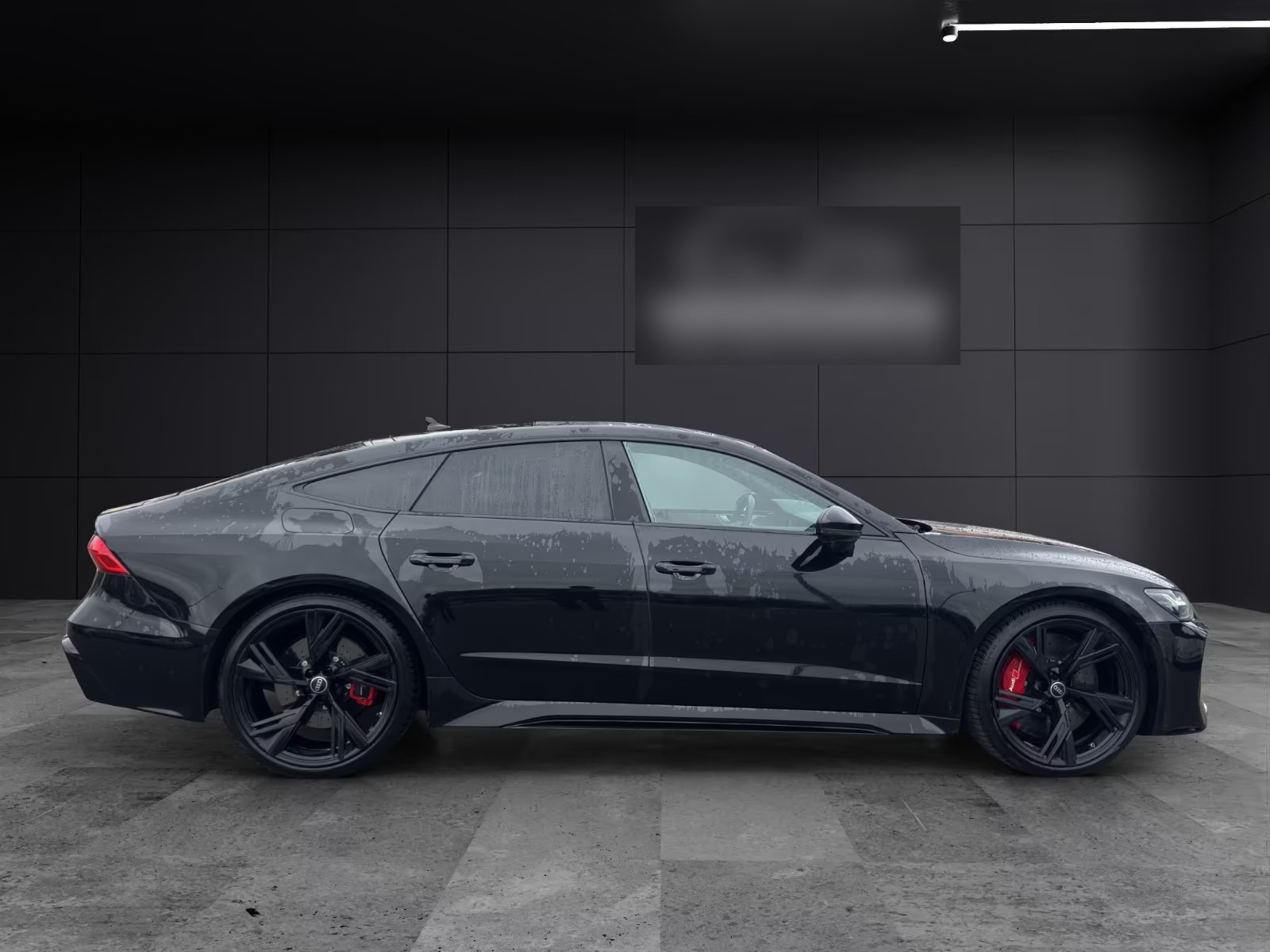 Passenger-side profile of the Audi RS7 Sportback in a dark showroom.