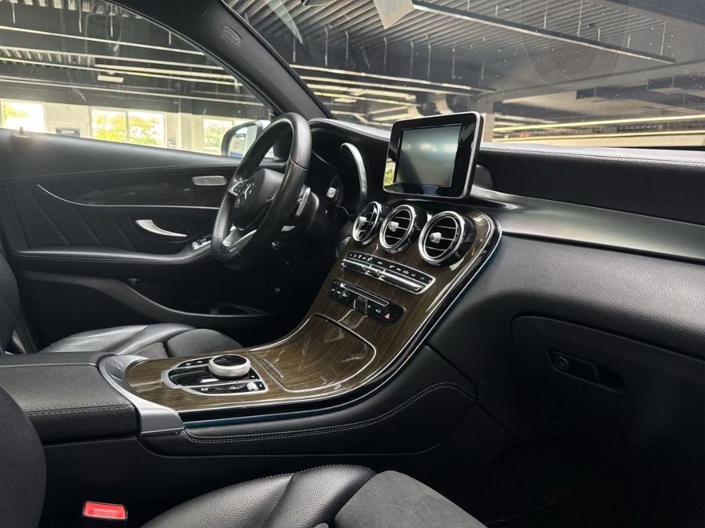 Interior of the Mercedes-Benz GLC seen from the passenger side, showing the dashboard, central display, turbine air vents and wood-trim centre console.