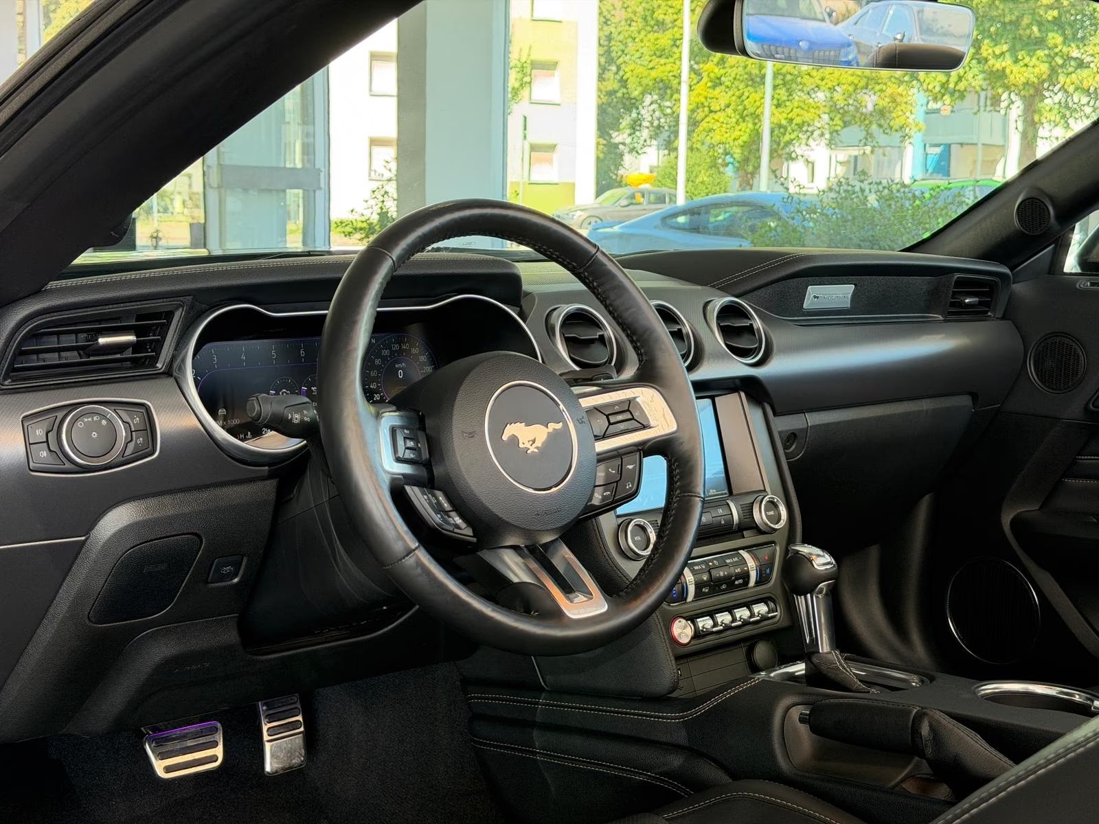 Driver cockpit of the Ford Mustang GT showing the leather steering wheel, instruments and centre touchscreen.