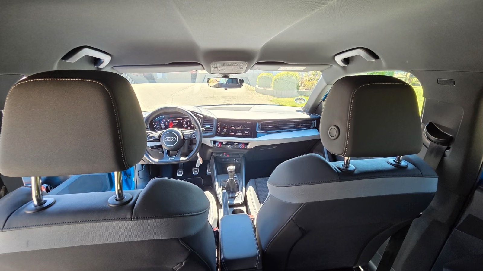 Interior of the Audi A1 viewed from the rear seats showing headrests, dashboard and black cloth upholstery.