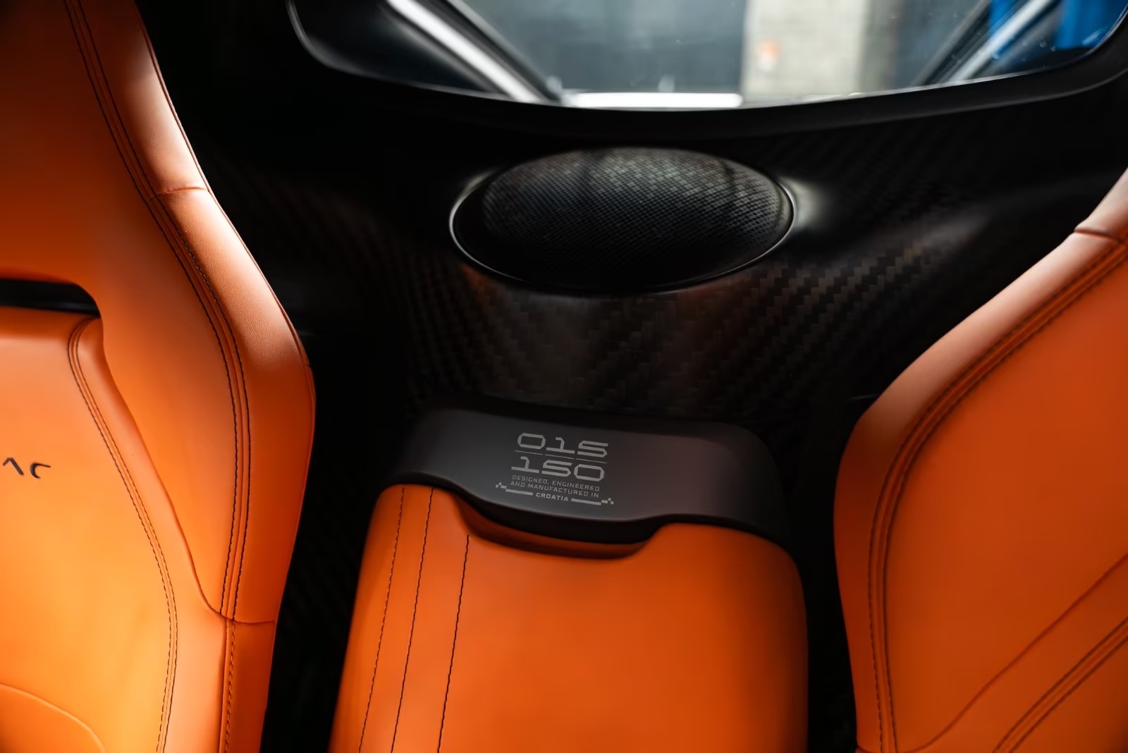 Numbered build plaque between the orange leather seats of the Rimac Nevera.