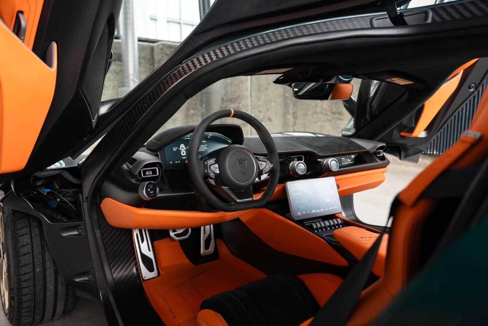 Rimac Nevera cockpit in Track Orange leather with carbon dashboard and touchscreen.