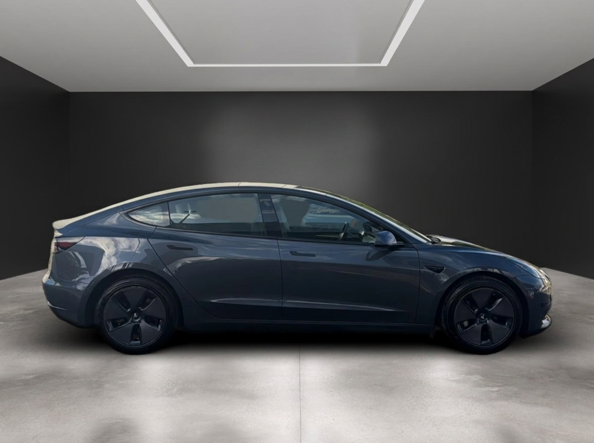Side profile of the grey Tesla Model 3 with its panoramic glass roof.