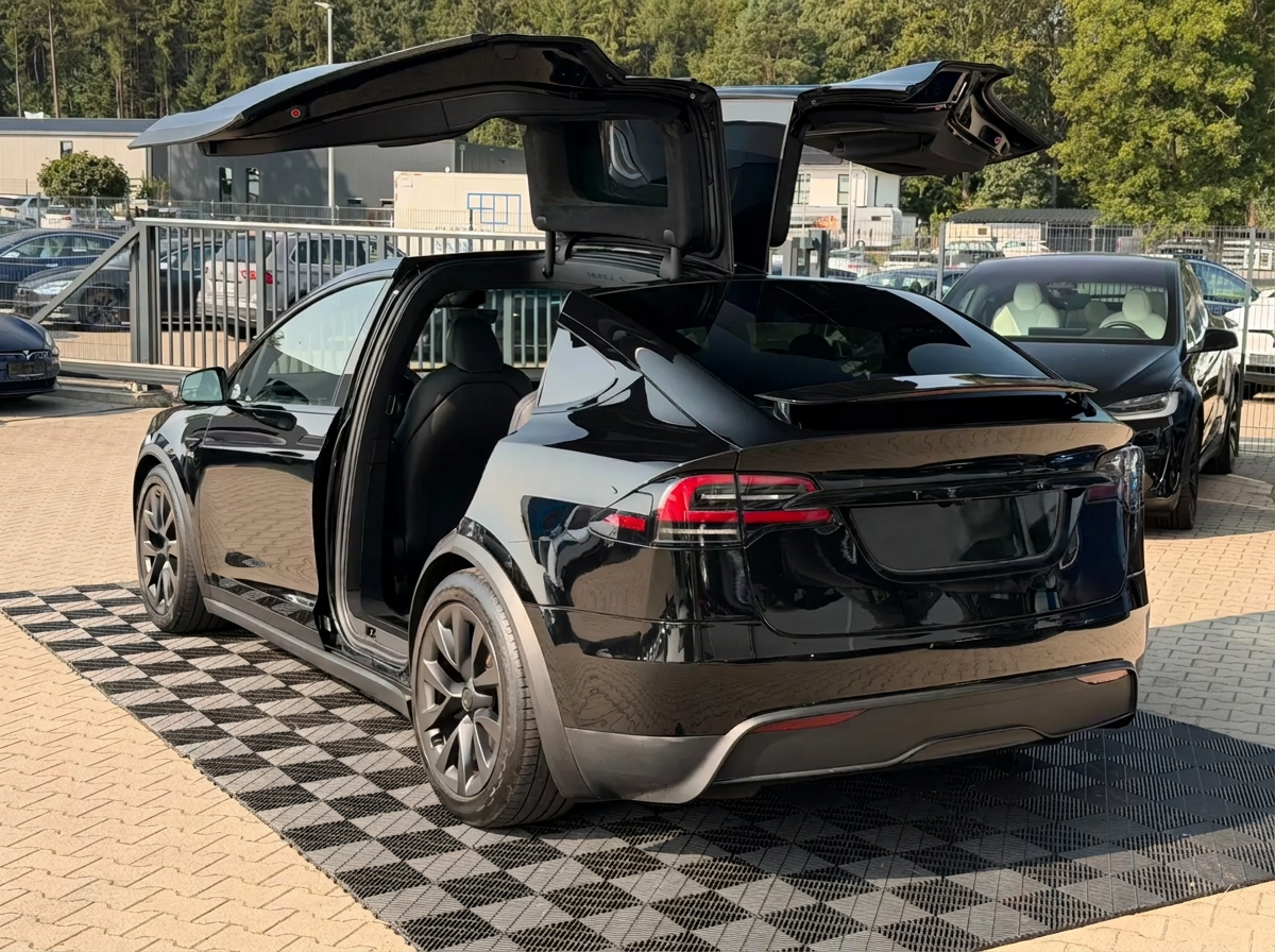 Rear three-quarter view of the Tesla Model X with falcon wing doors raised.