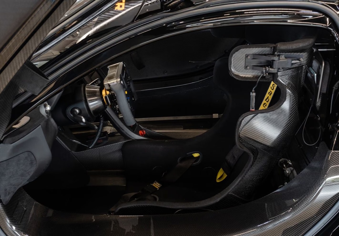 Carbon fibre cockpit of the McLaren P1 GTR with racing seat and harness, seen through the open door.