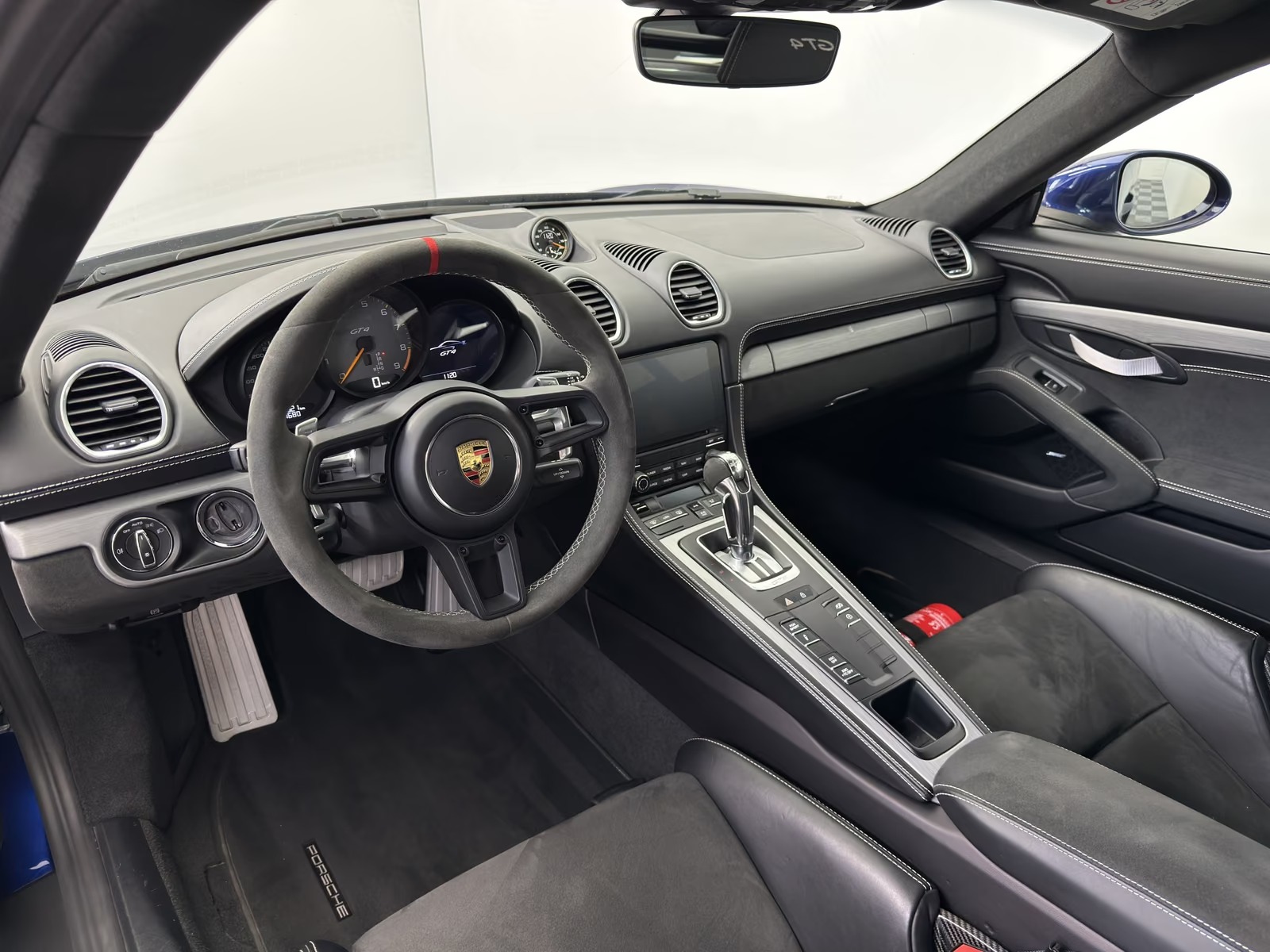 Driver view of the Porsche 718 Cayman GT4 showing the Alcantara steering wheel, GT4 instrument cluster and PCM touchscreen.