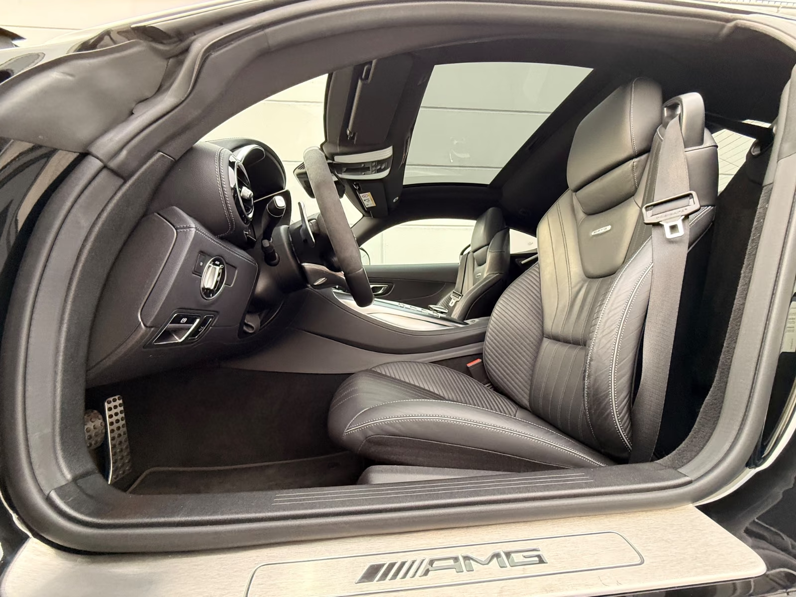 Driver seat of the Mercedes-AMG GT C in black leather with AMG door sill trim.