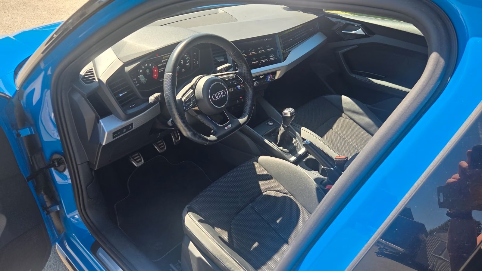 Driver-side interior of the Audi A1 showing the sport seats, steering wheel, digital cockpit and manual gear lever.
