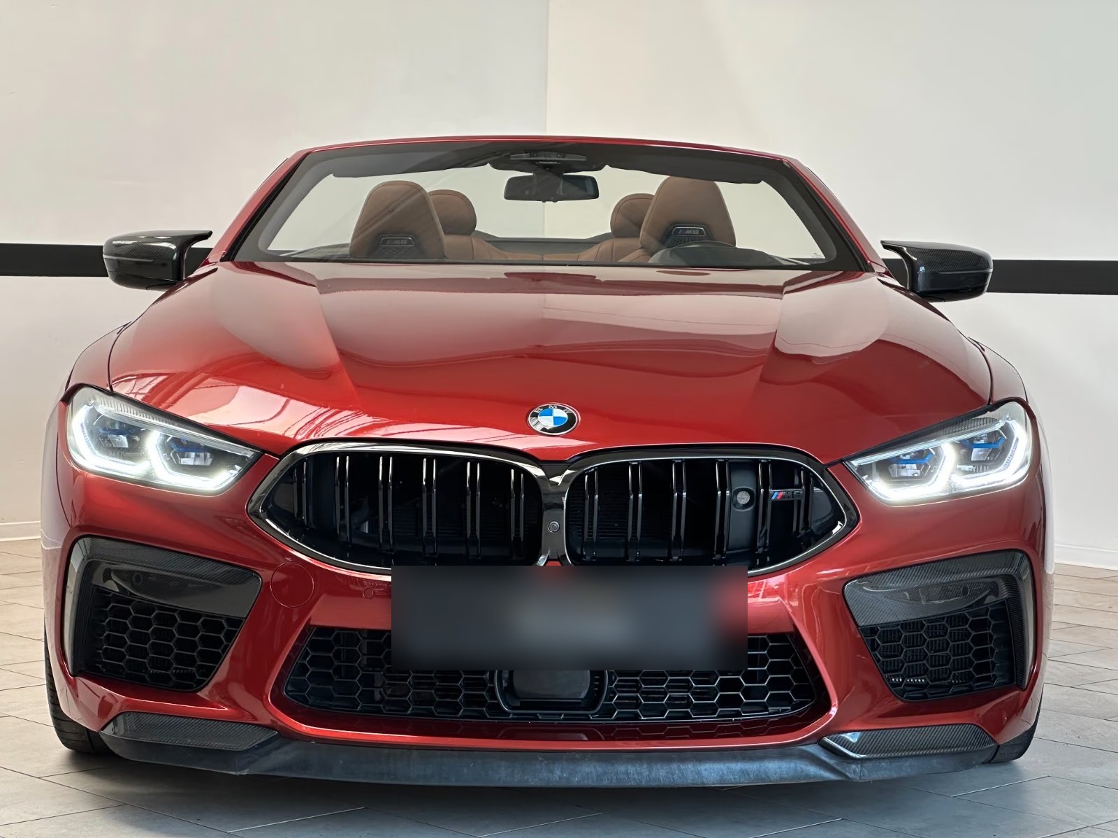 Head-on front view of the red BMW M8 Competition Cabrio showing the black kidney grille and laser headlights.
