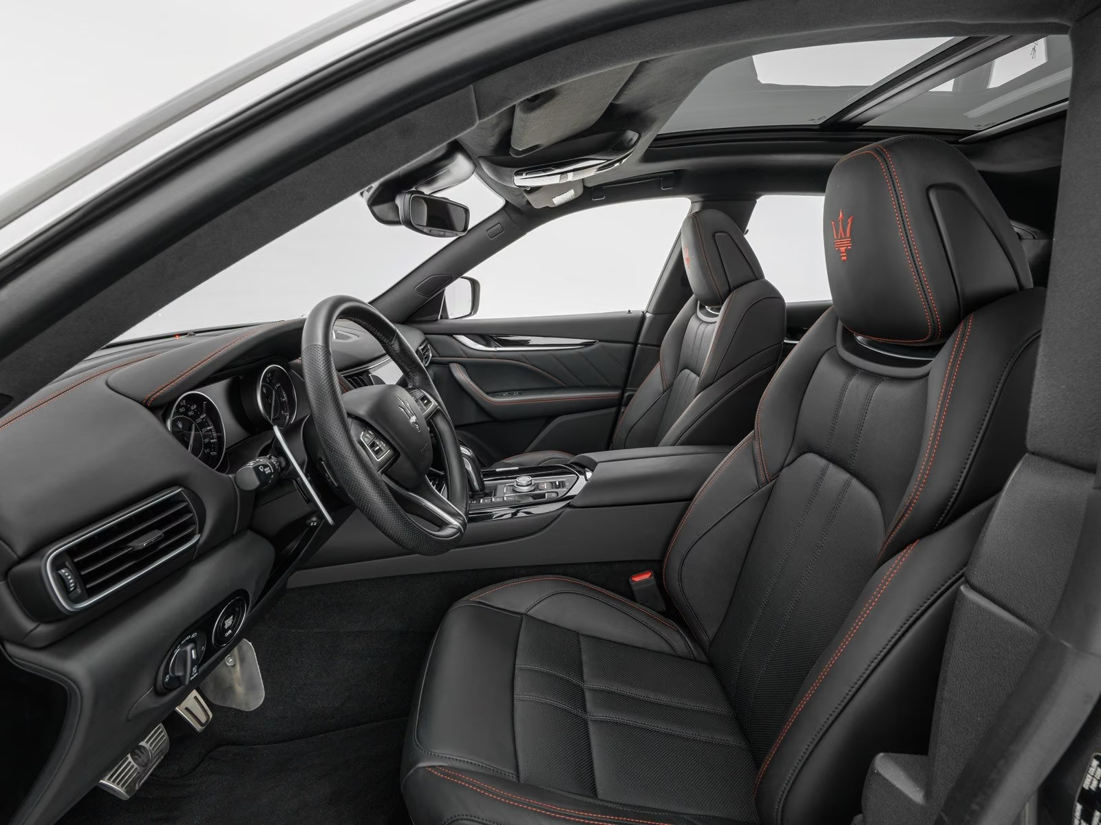 Nero leather front seats with red stitching and trident-embroidered headrests.