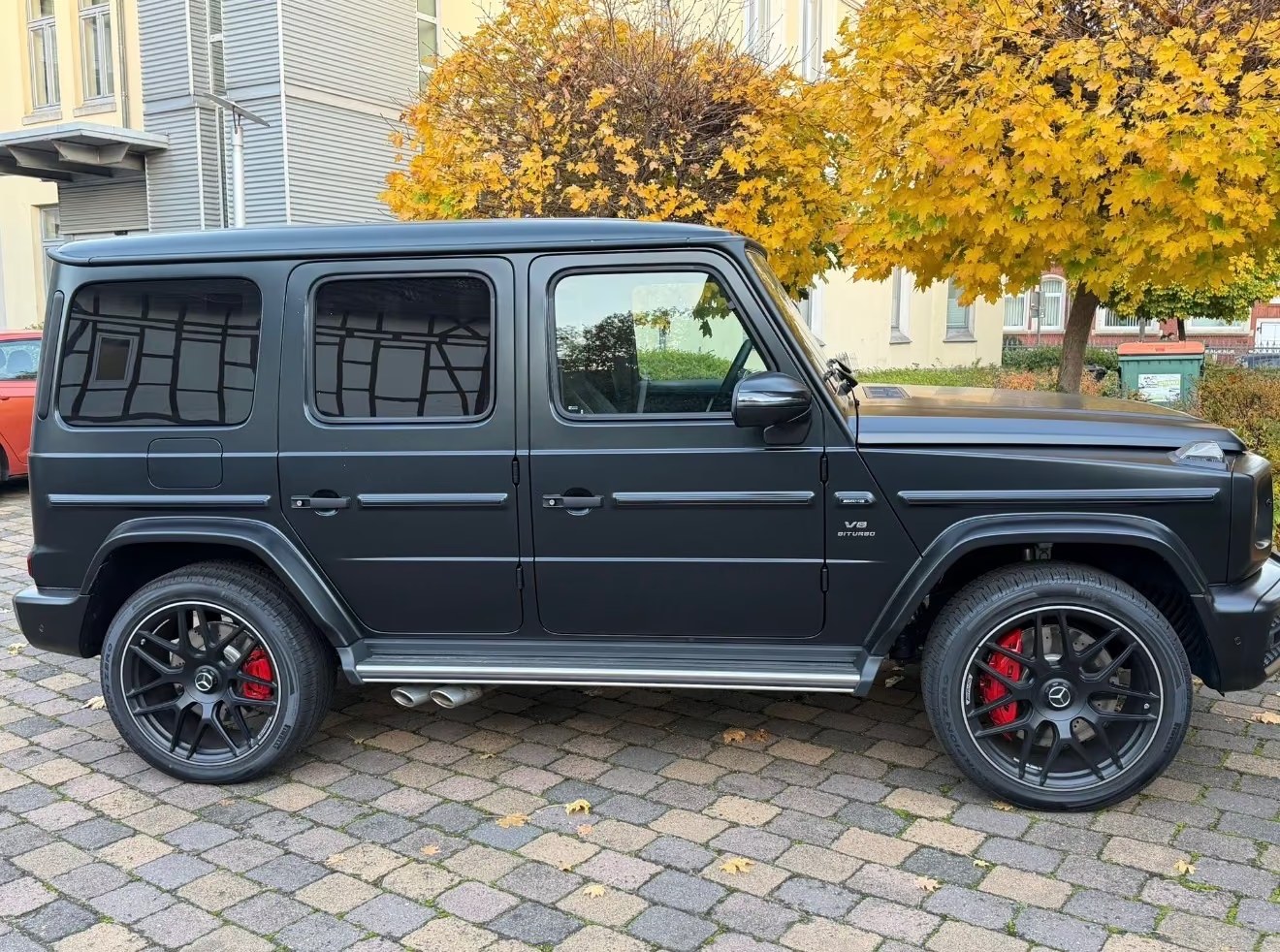 Matte black Mercedes-AMG G 63 in full side profile on cobblestone.