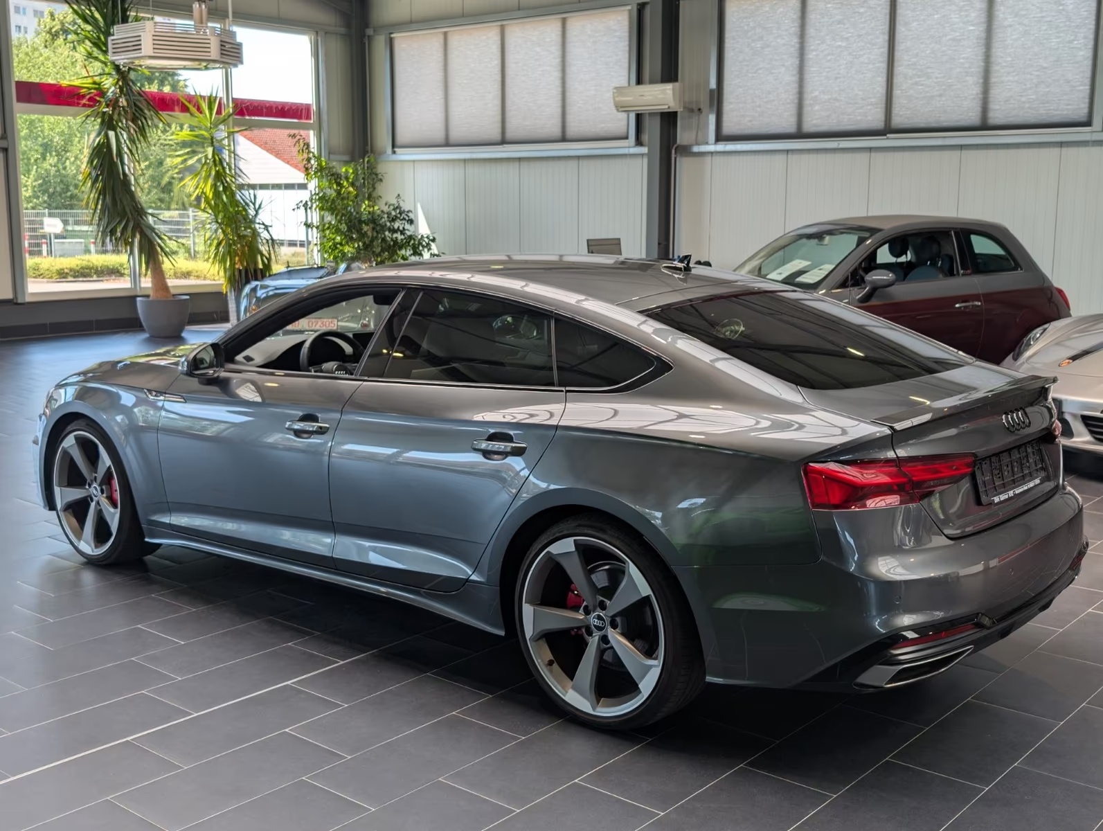 Rear three-quarter view of the Audi A5 Sportback from the driver side, showing the sloping roofline, alloy wheel and rear light.