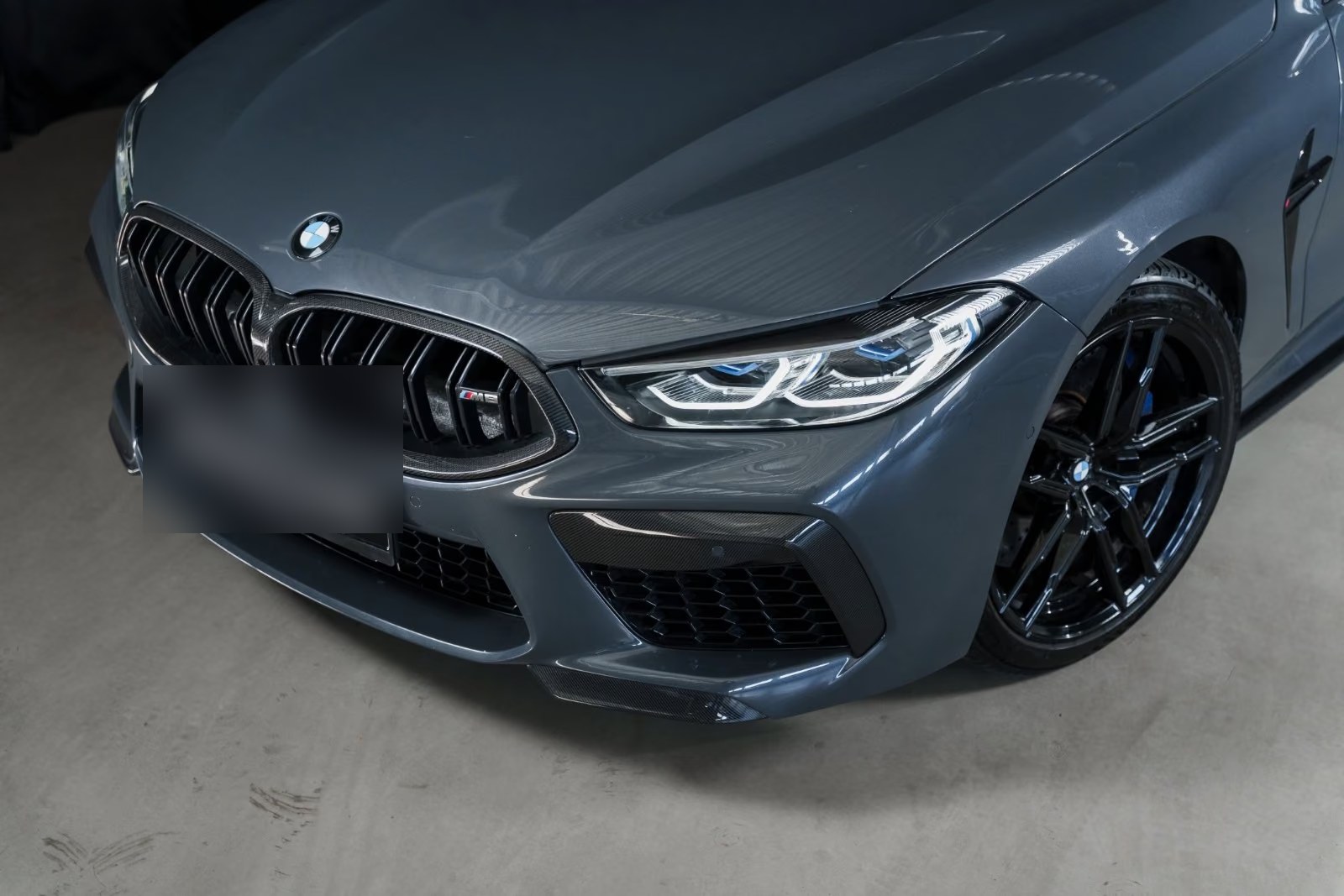 Close-up of the BMW M8 front end showing the carbon grille surround, air intakes and blue brake calipers.