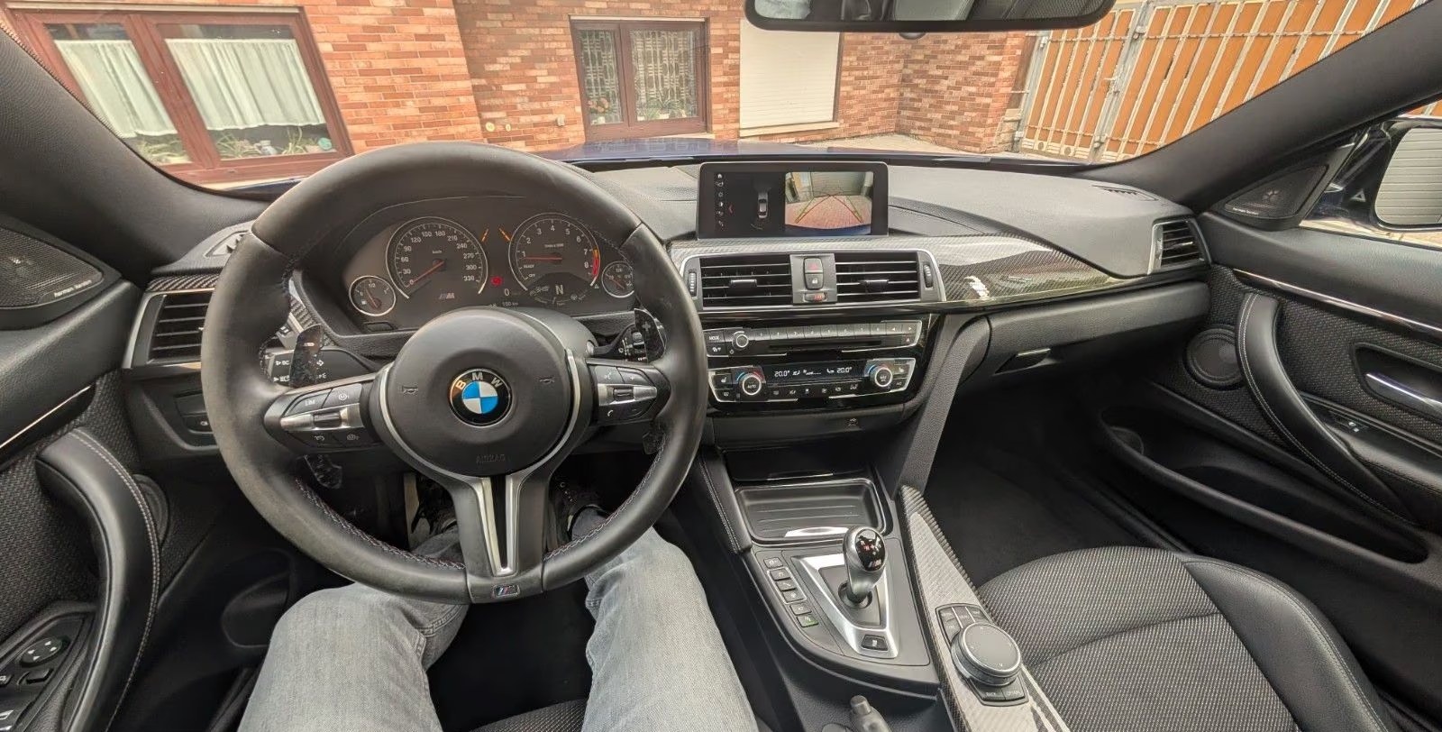 M4 cockpit view with M steering wheel, instruments and reversing camera display.