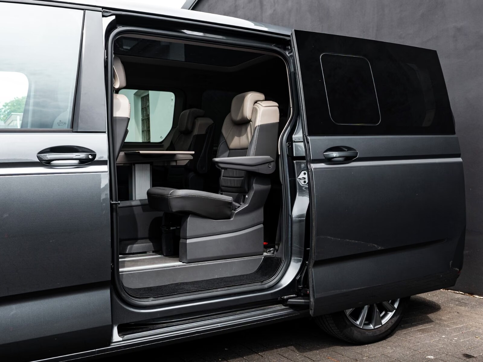 Second-row seating of the T7 Multivan with folding table, seen through the open sliding door.