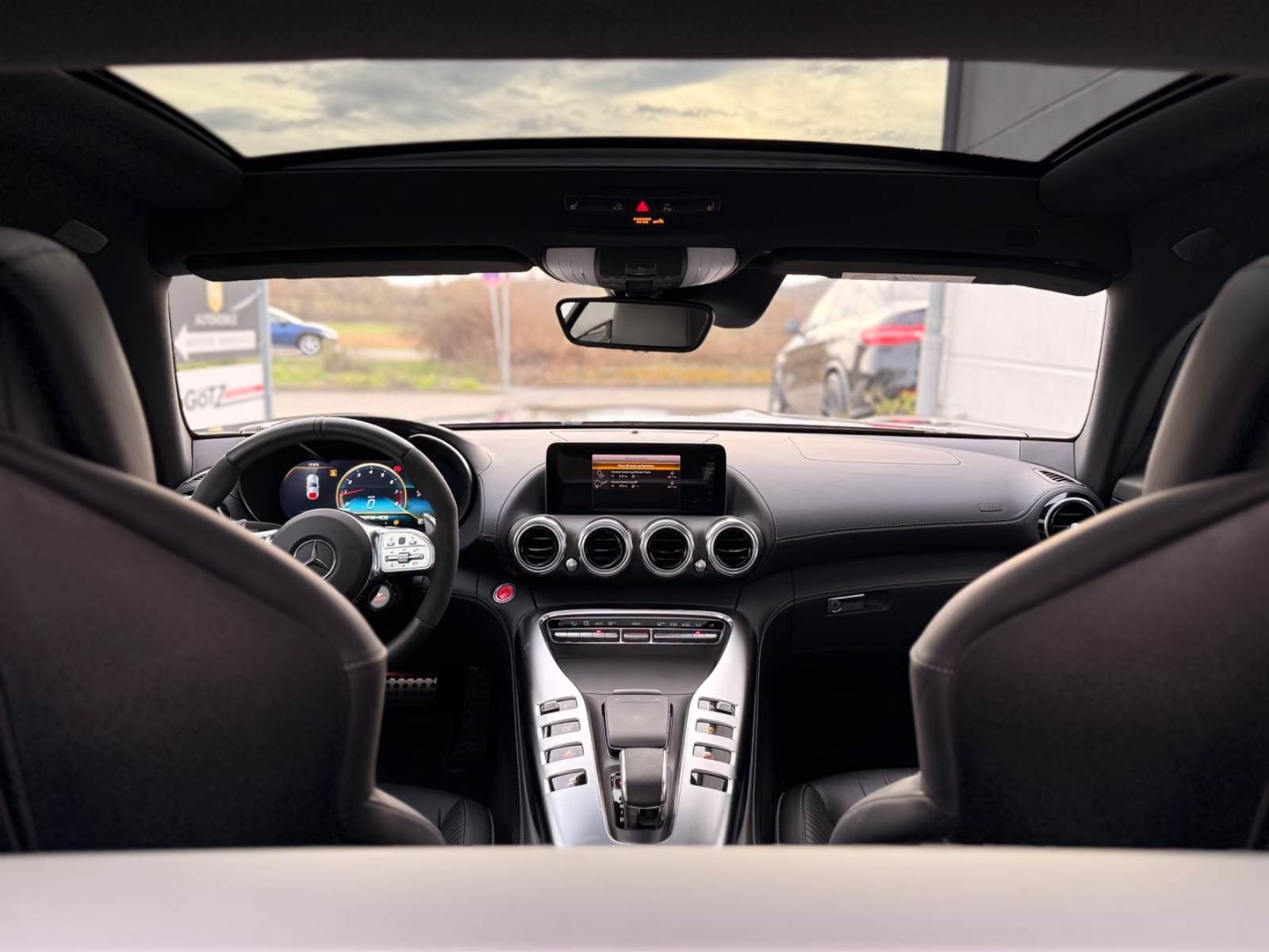 Cabin of the Mercedes-AMG GT C seen from behind the seats, showing the panoramic roof and centre console.