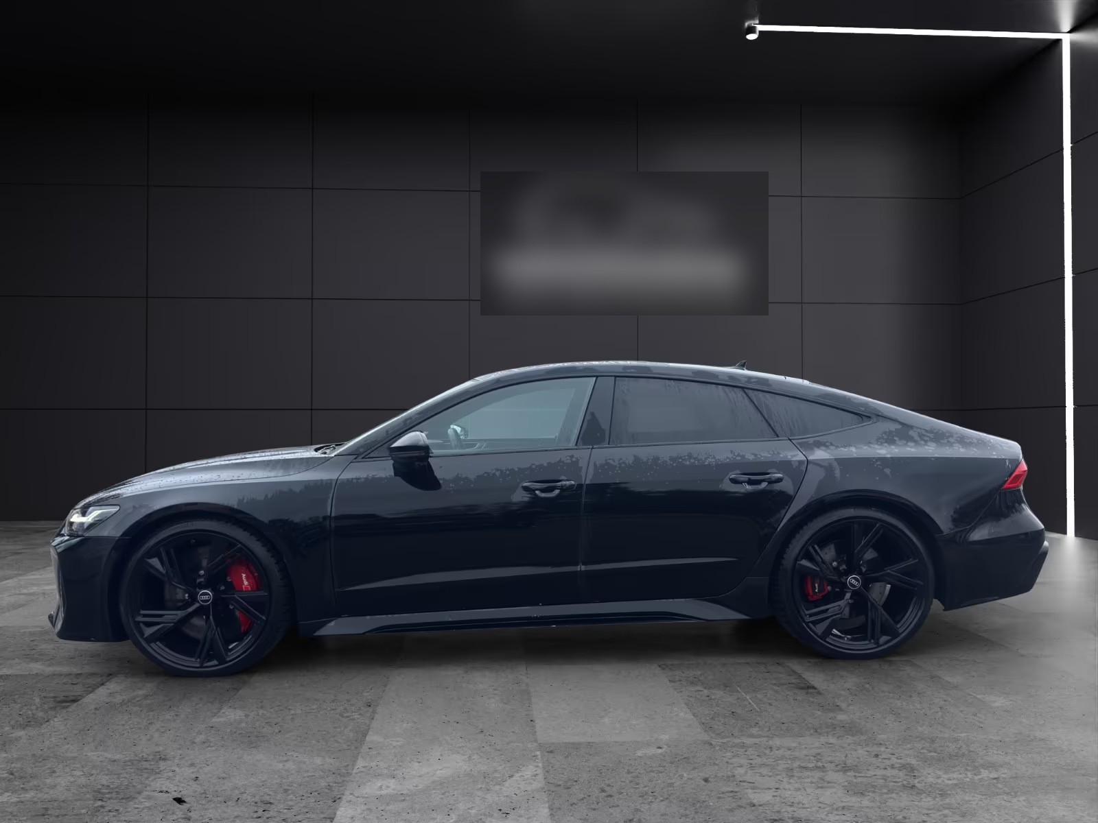 Side profile of the black Audi RS7 Sportback showing the 22-inch black Audi Sport wheels and red brake calipers.