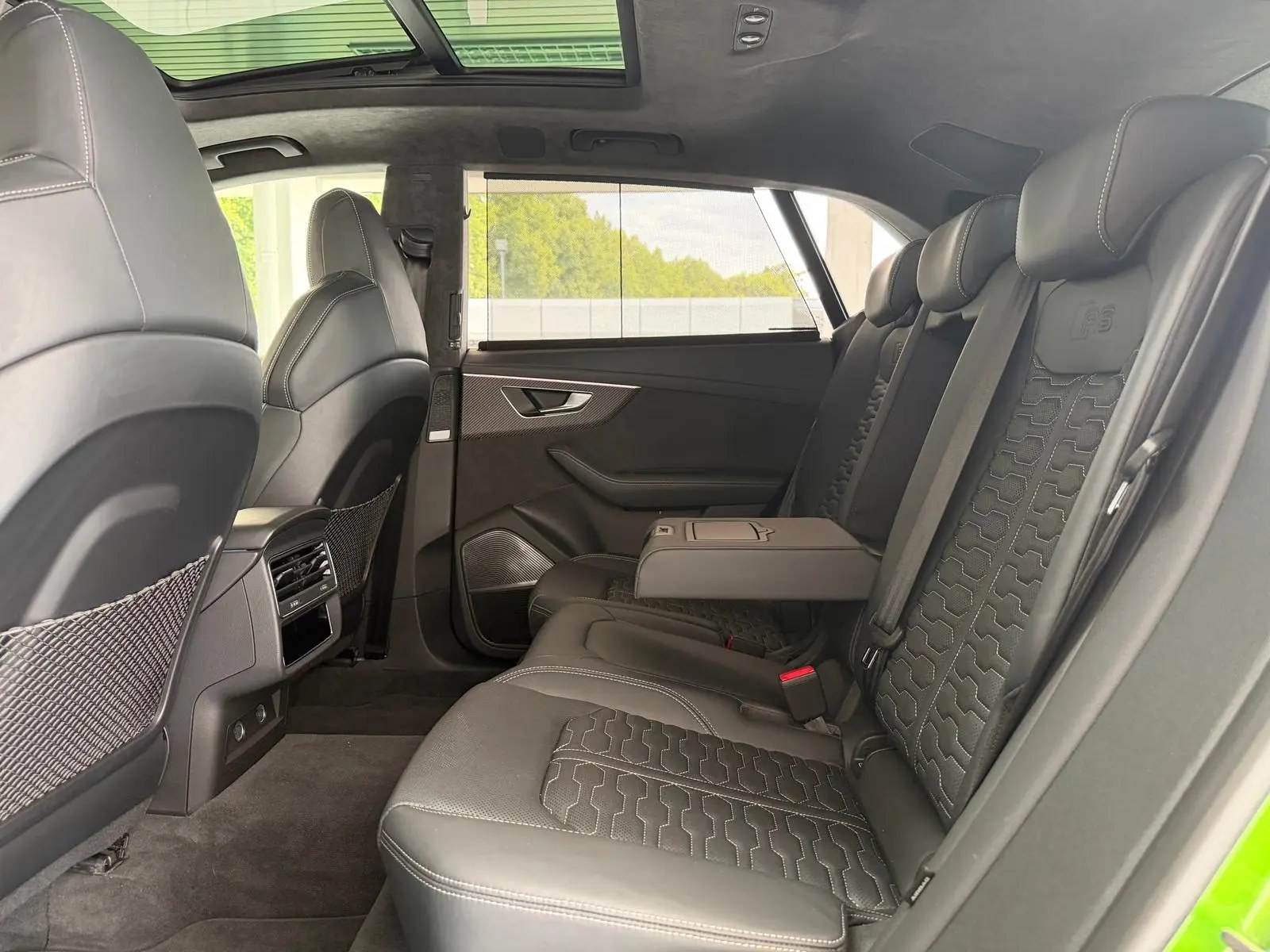 Rear seats of the Audi RS Q8 in black leather beneath the panoramic glass roof.