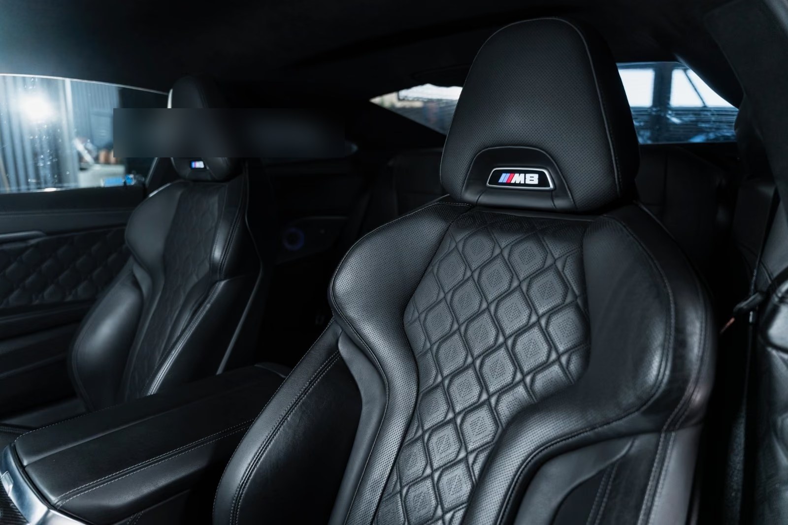 Black diamond-quilted leather sport seats of the BMW M8 with M8 badged headrests.