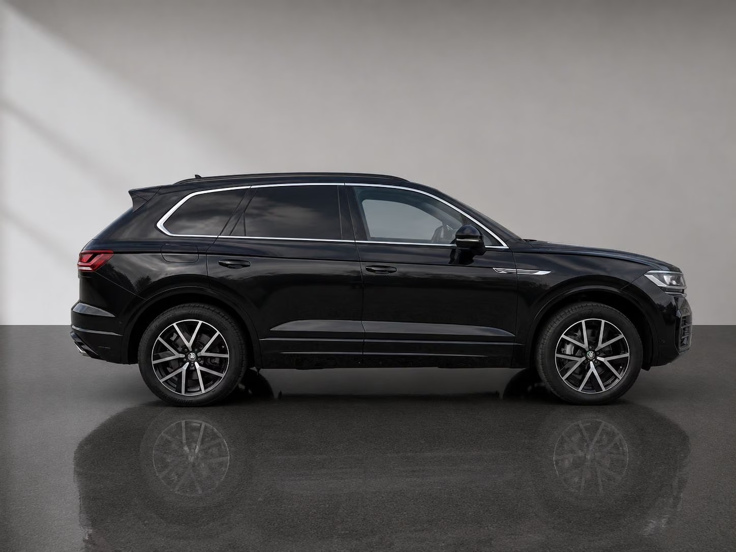 Side profile of the black Volkswagen Touareg R-Line with chrome window trim and roof rails.