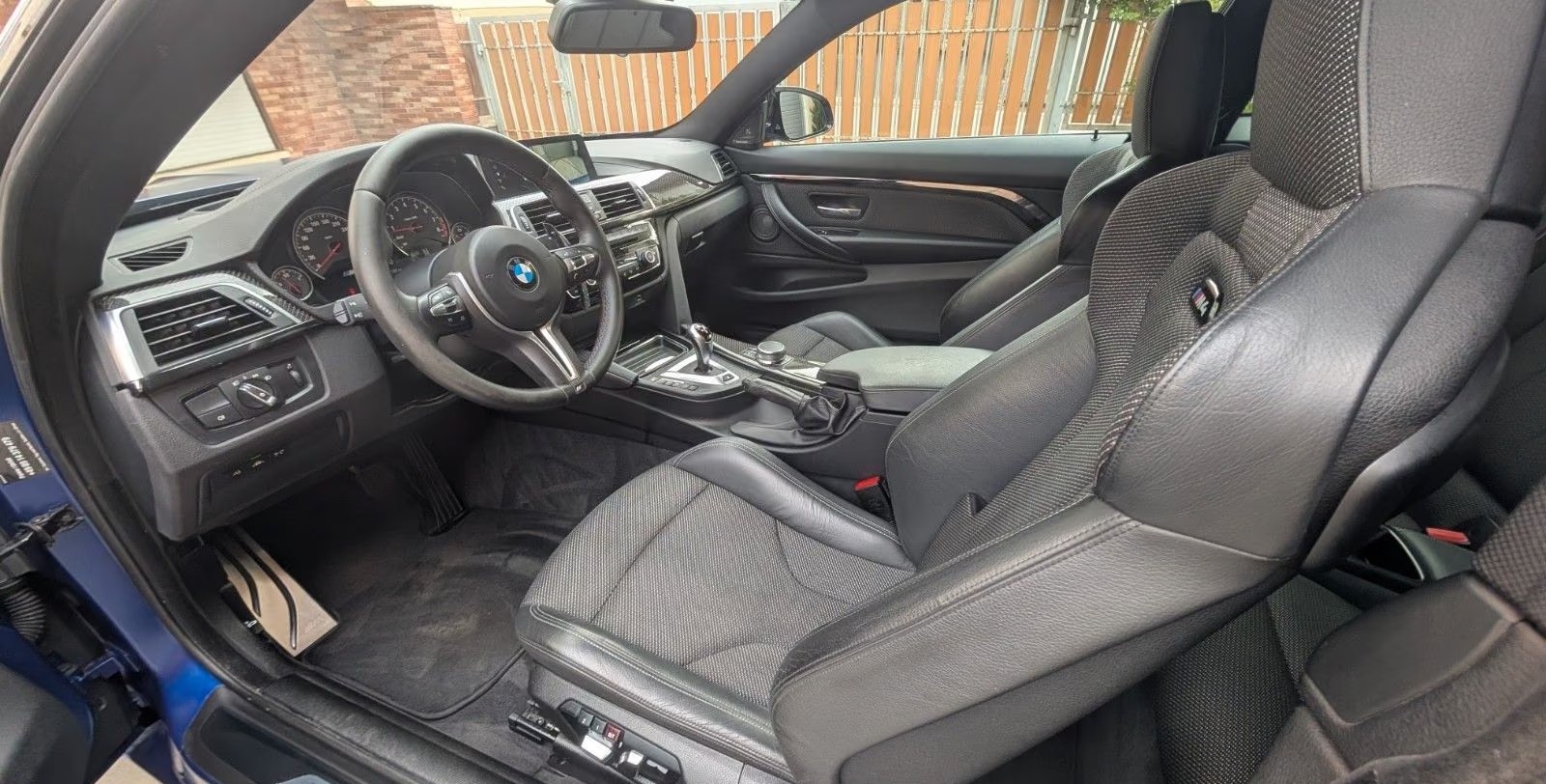 Driver's side interior of the M4 with sport seats and carbon trim.
