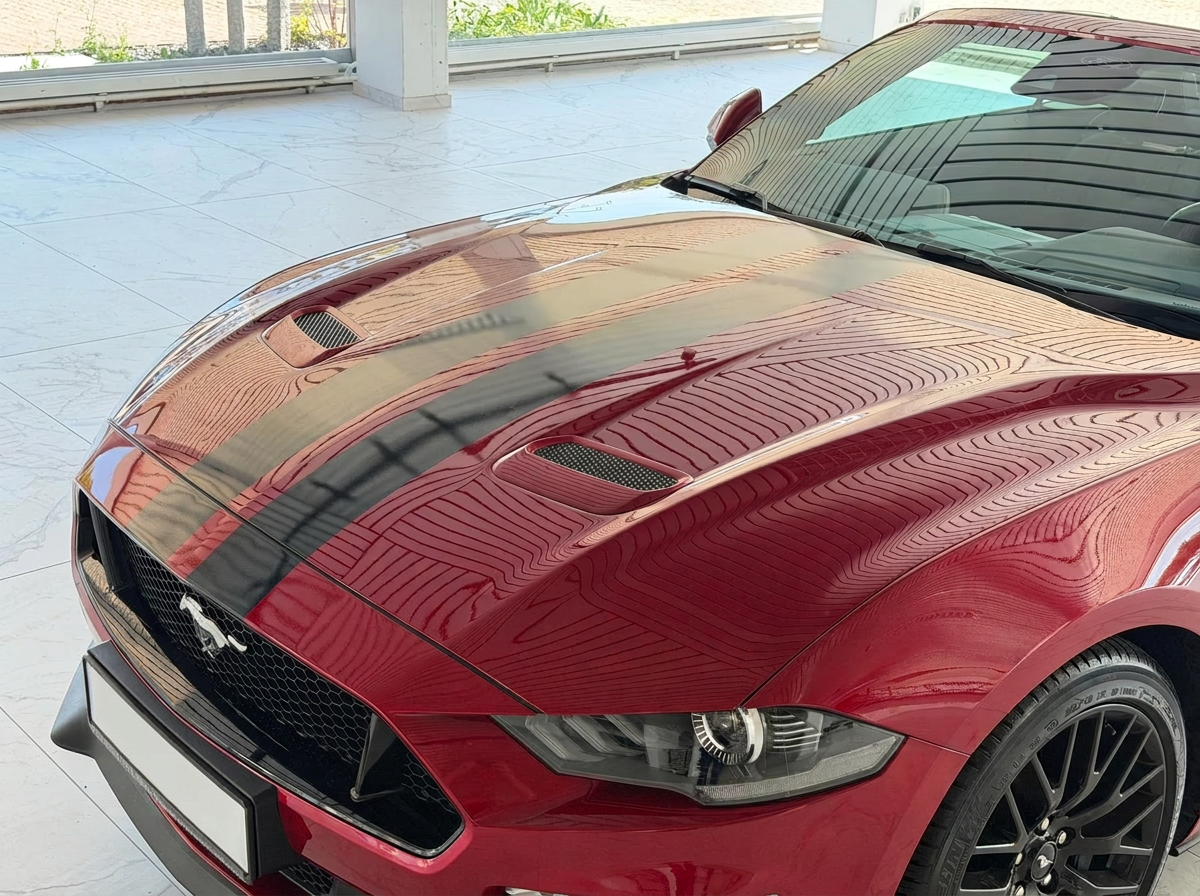 Close-up of the red Ford Mustang GT Convertible bonnet with black racing stripes and hood vents.