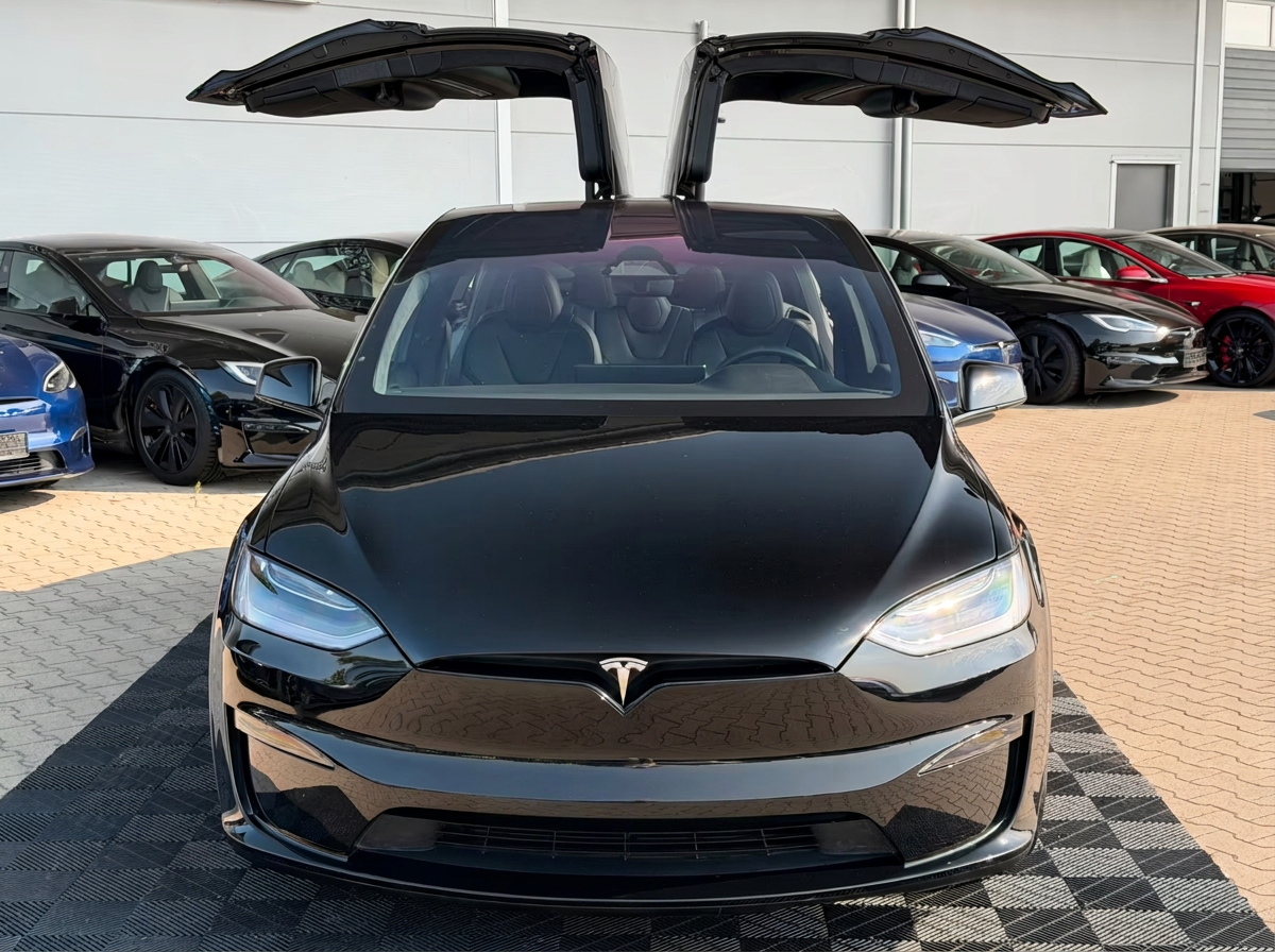 Front view of the black Tesla Model X with both falcon wing doors open.