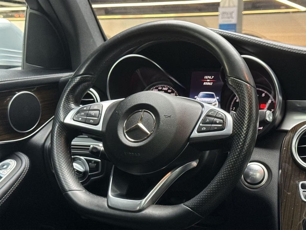Driver view of the Mercedes-Benz GLC showing the leather multifunction steering wheel with paddle shifters and the instrument cluster.