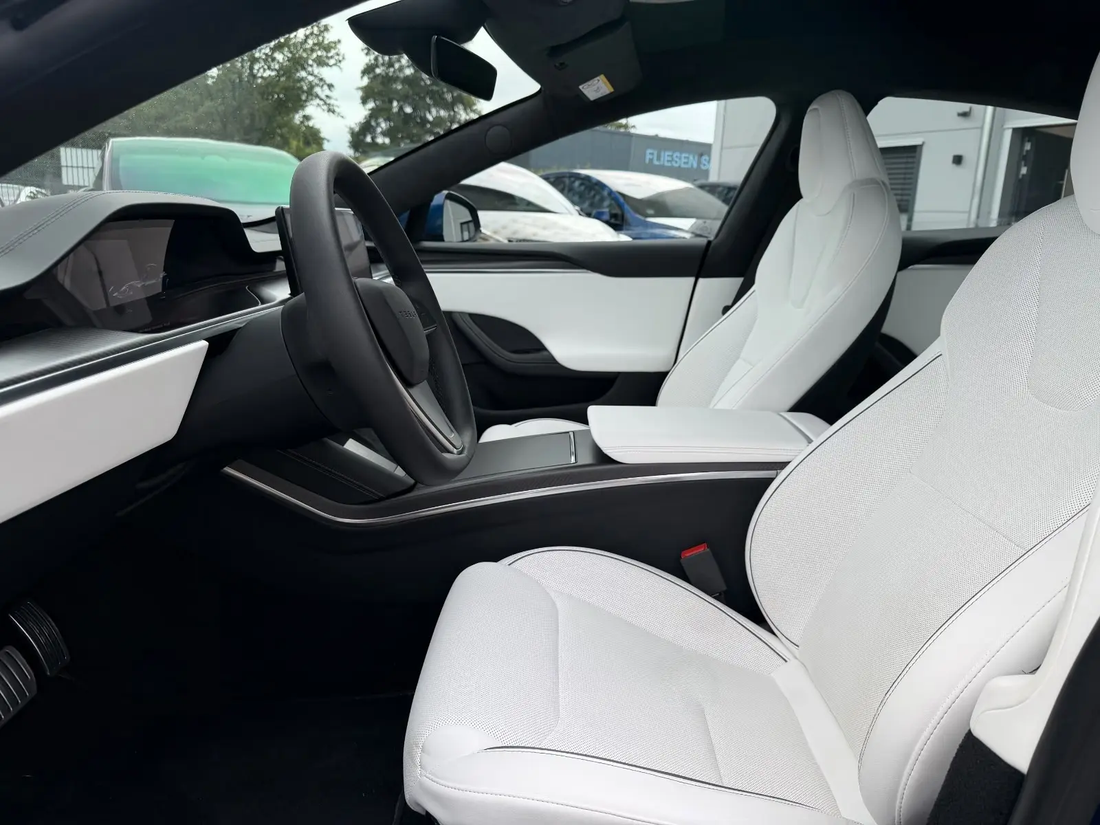 Front cabin of the Tesla Model S Plaid with yoke steering wheel and white seats.