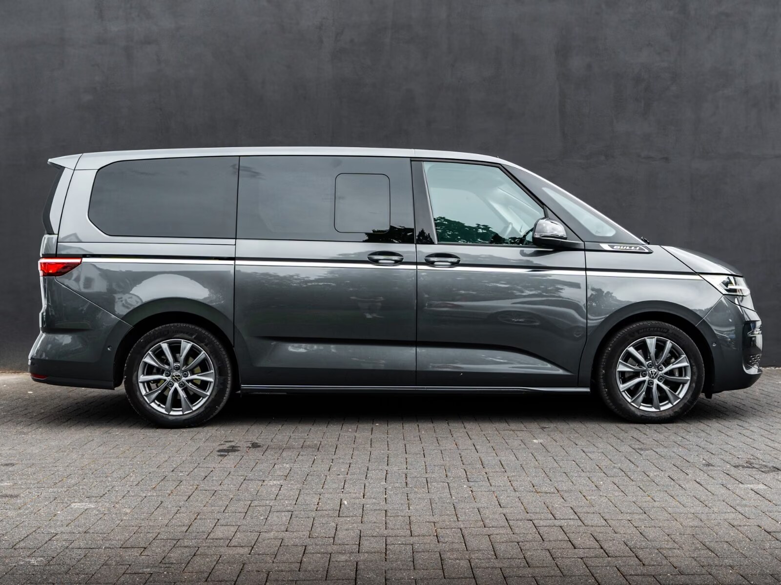 Side profile of the grey Volkswagen T7 Multivan on paving.