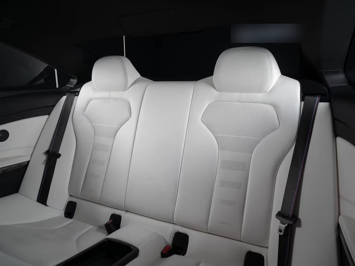 Rear bench of the BMW M4 in Opal White leather with M-striped seat belts.