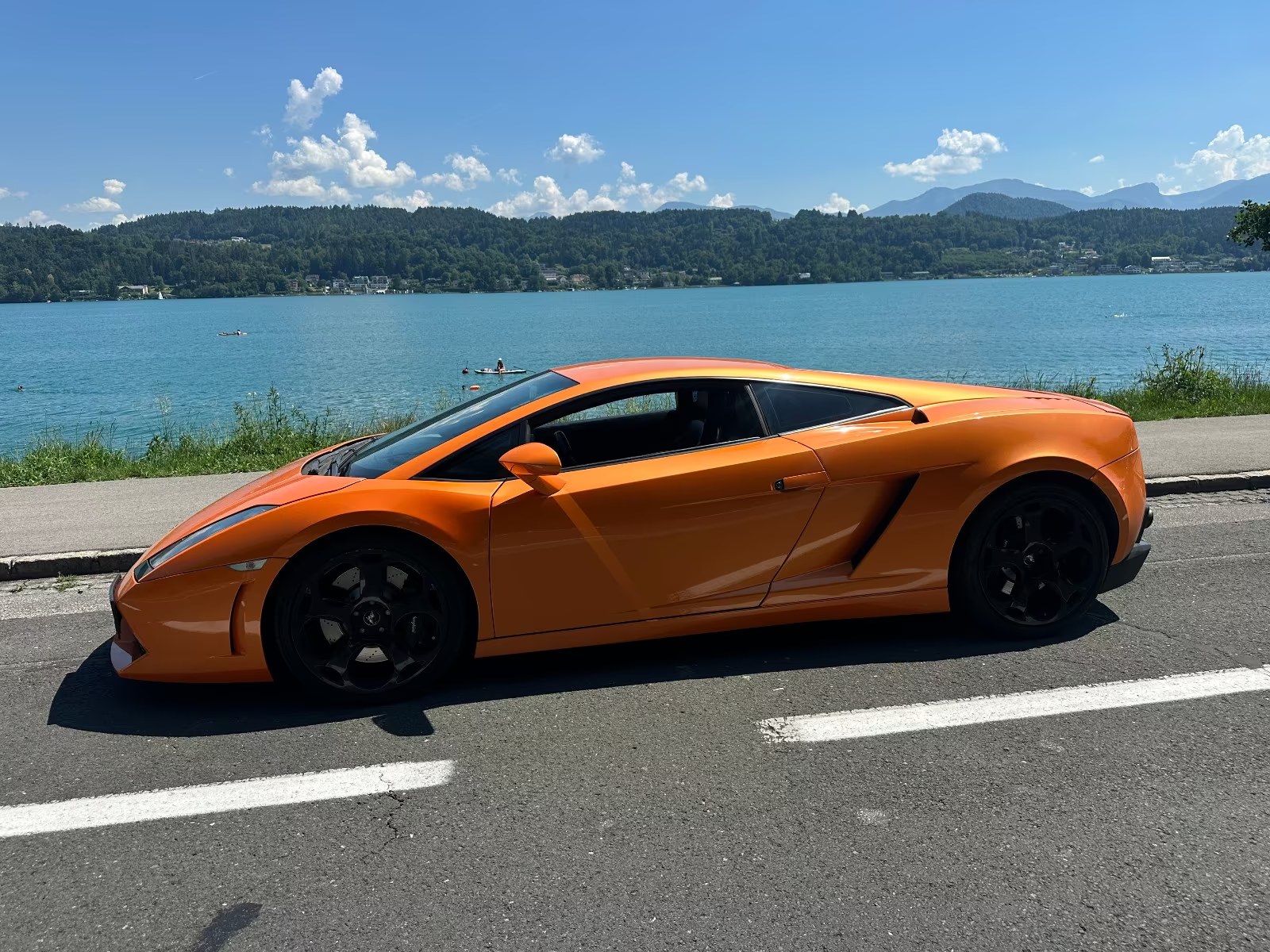 Orange Lamborghini Gallardo side profile parked beside a lake