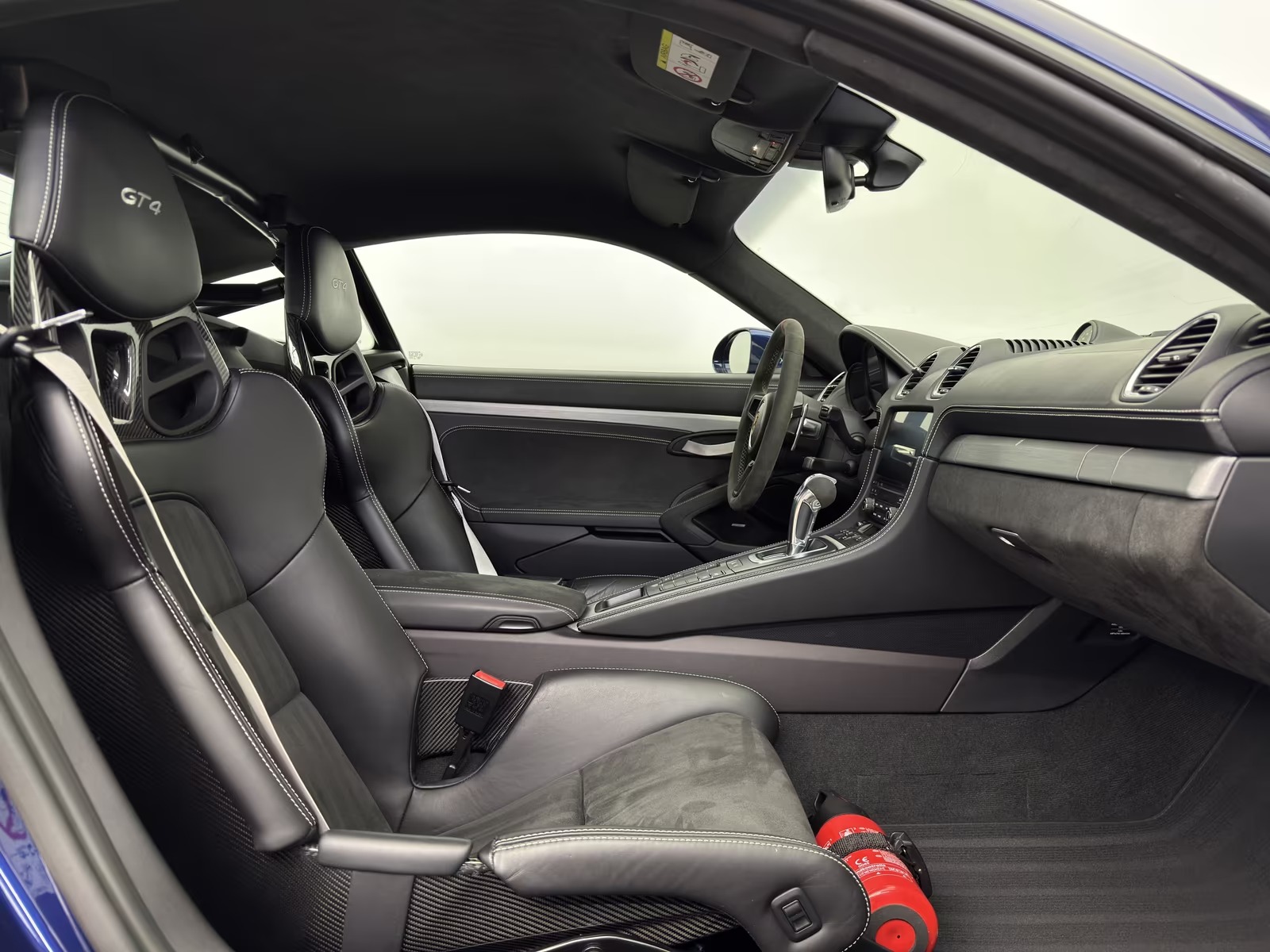 Interior of the Porsche 718 Cayman GT4 seen from the driver side, showing both seats, the dashboard and the centre console.
