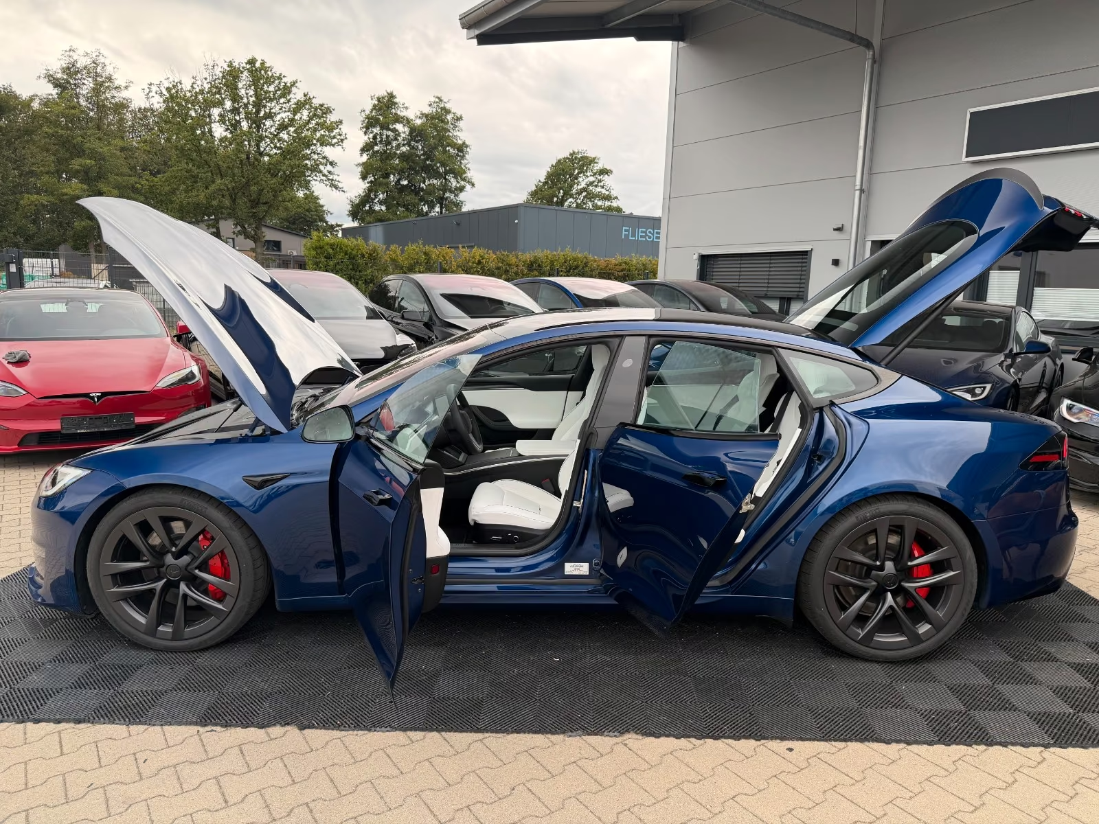 Tesla Model S Plaid with all doors, frunk and tailgate open showing the white interior.