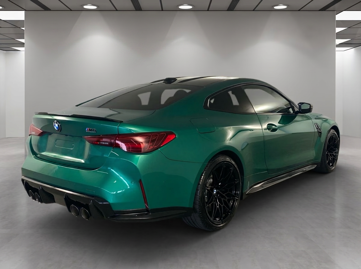 Rear three-quarter view of the green BMW M4 with quad exhausts and M badge.