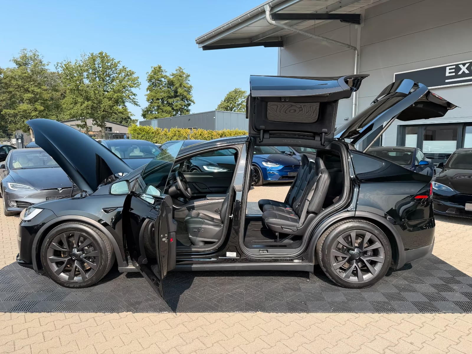 Tesla Model X with all doors and falcon wings open showing the seven-seat cabin.