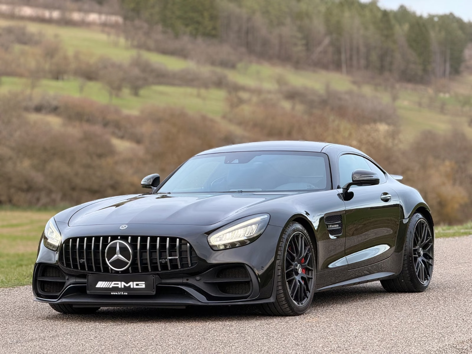 Mercedes-AMG GT C Coupé in Obsidian Black metallic, front three-quarter view showing the Panamericana grille and LED headlights.
