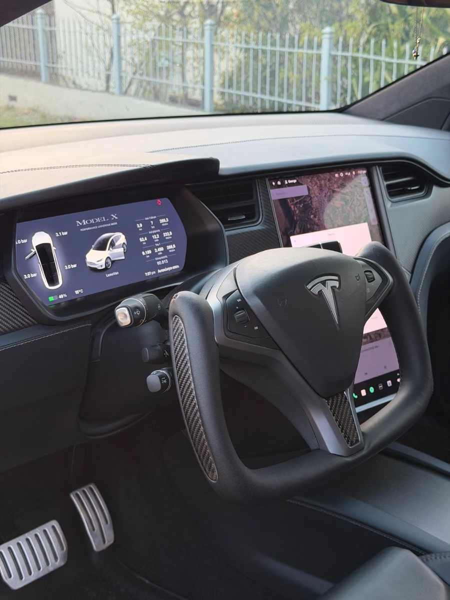 Tesla Model X cockpit with carbon yoke steering wheel and digital driver display.