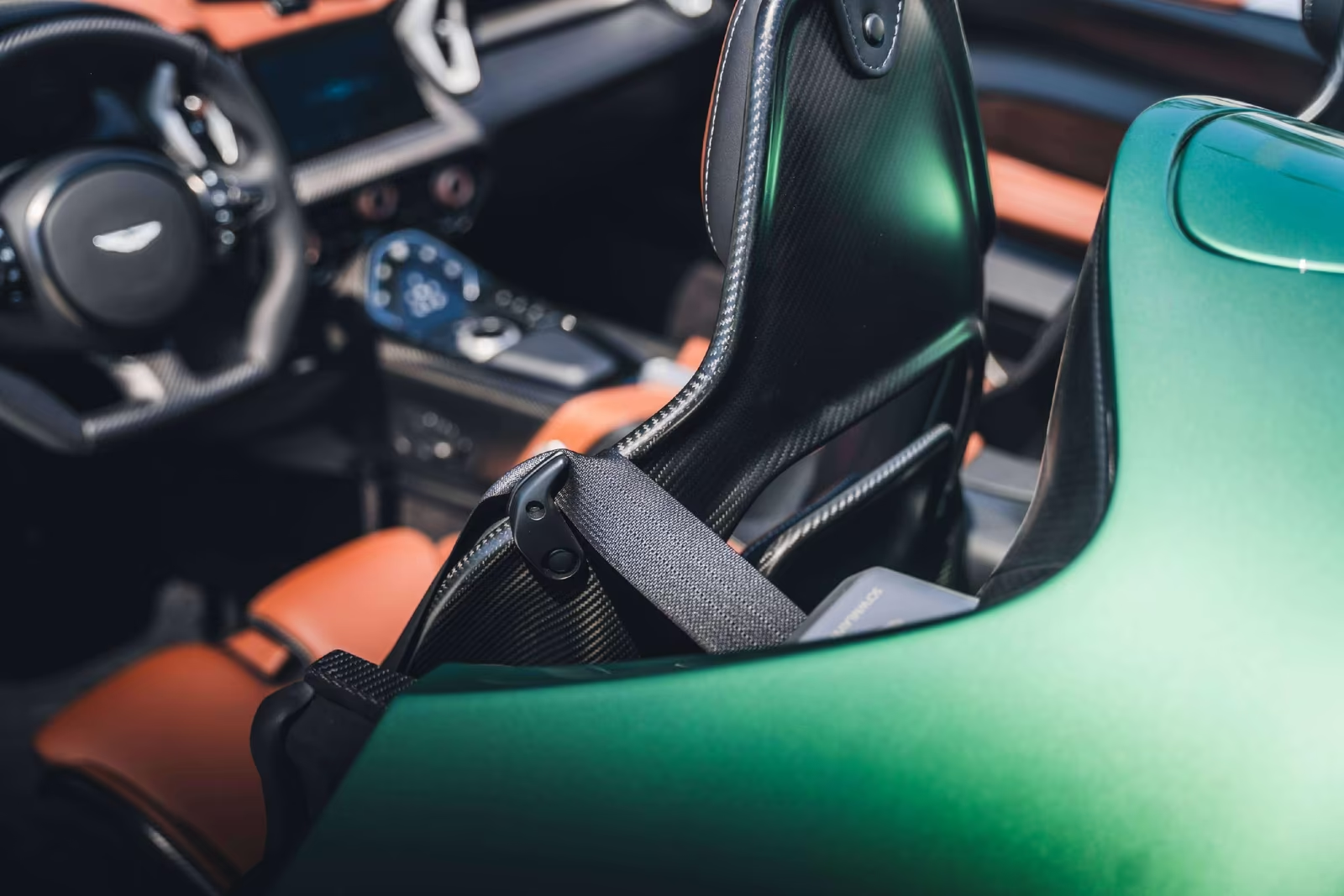 Close-up of the DBR22 carbon fibre seat back and harness with the tan leather cabin behind.