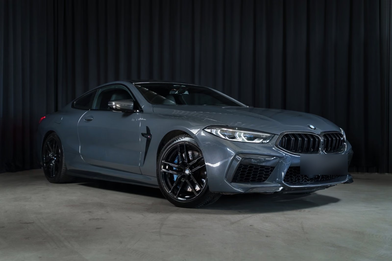 Front three-quarter view of the BMW M8 Coupé from the passenger side with black M alloy wheels.