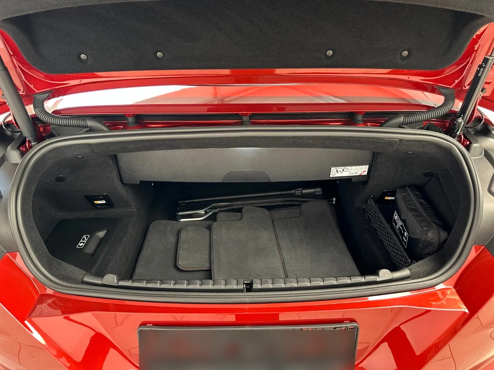 Open boot of the red BMW M8 Cabrio showing the carpeted luggage compartment.