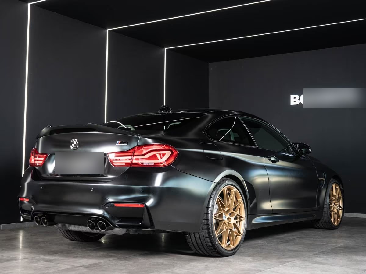 Rear three-quarter view of the BMW M4 Competition with quad exhaust tips and boot spoiler.