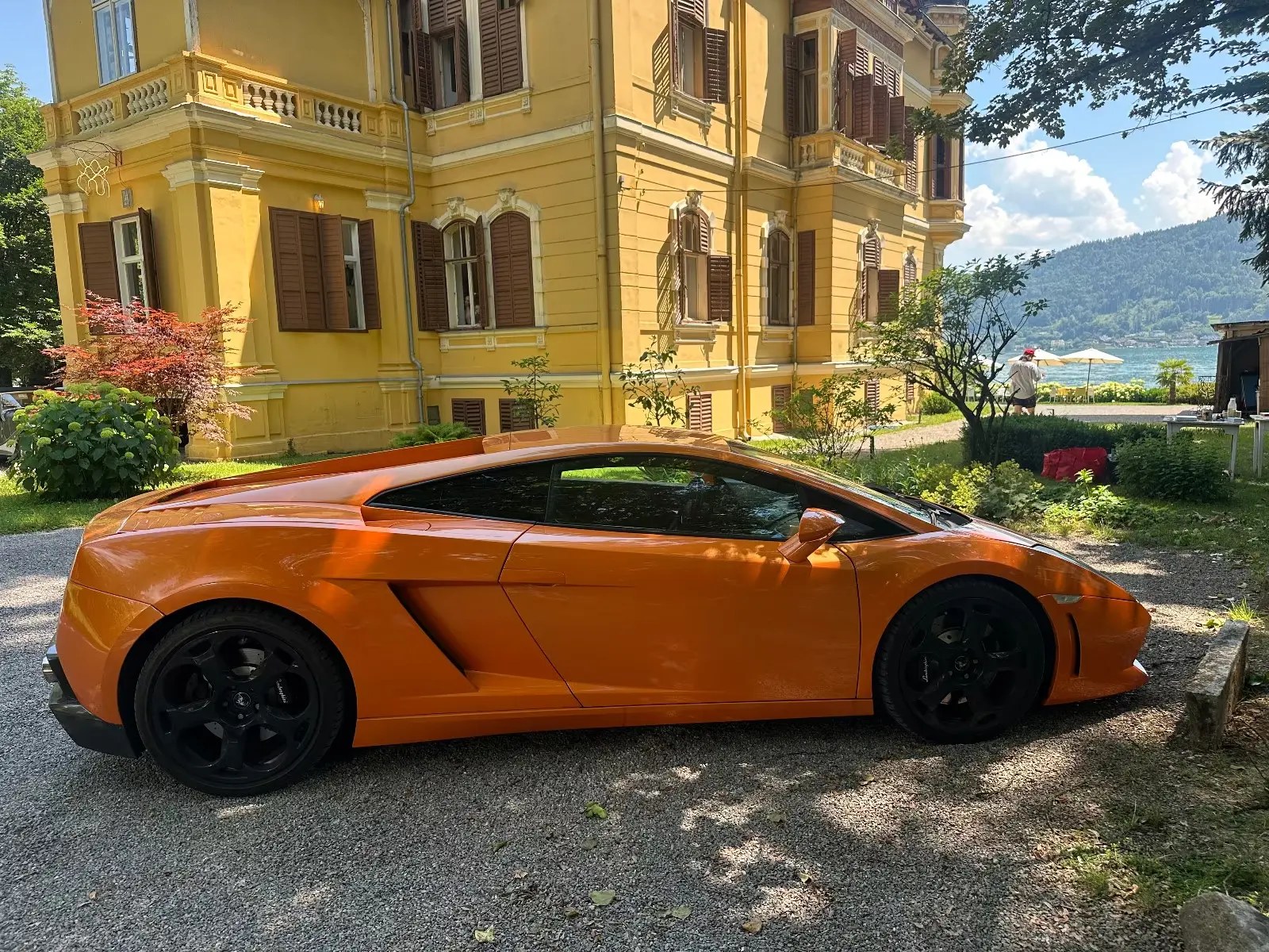 Orange Lamborghini Gallardo side view in front of a villa