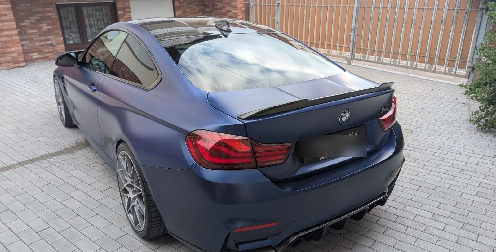 Rear three-quarter view of the BMW M4 Competition with carbon boot spoiler and diffuser.