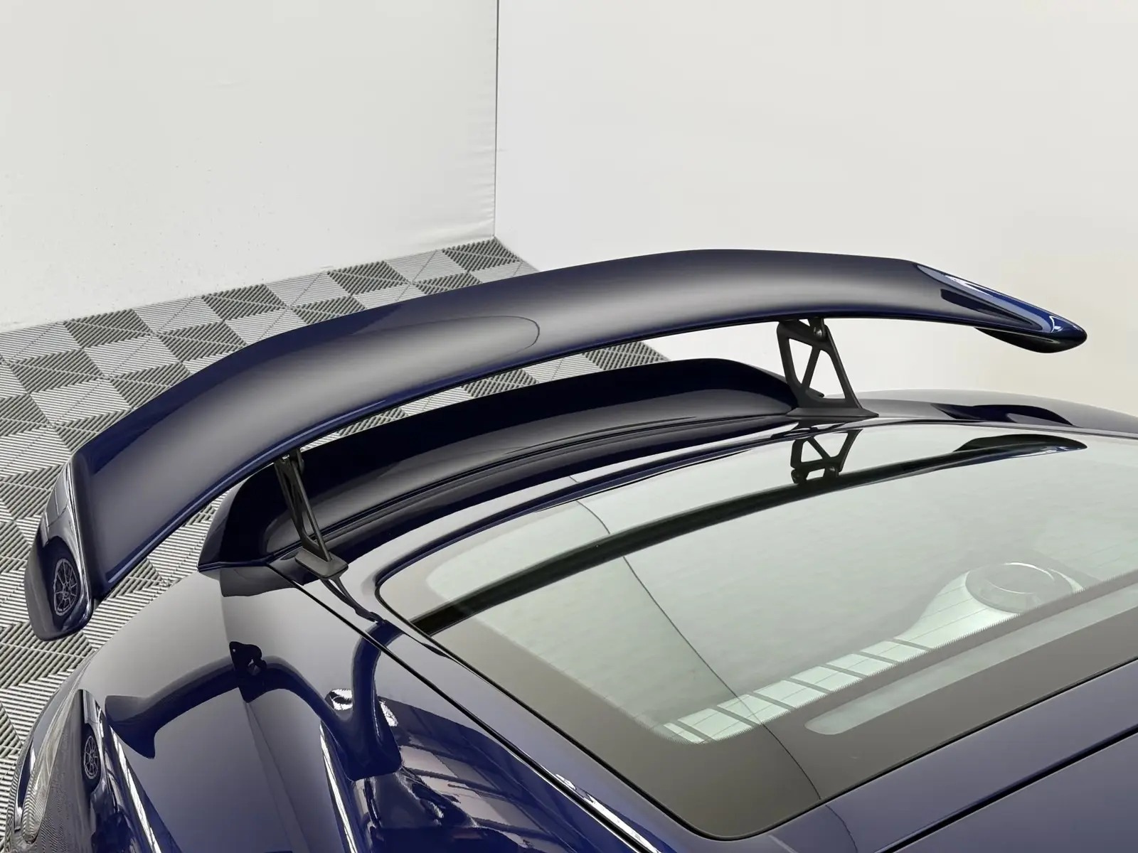 Close-up of the fixed rear wing of the Porsche 718 Cayman GT4 above the rear window.