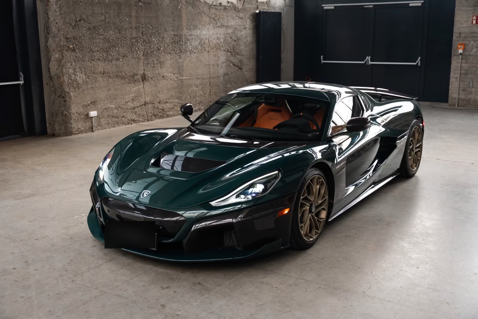 Rimac Nevera in British Racing Green, front three-quarter view in a showroom.